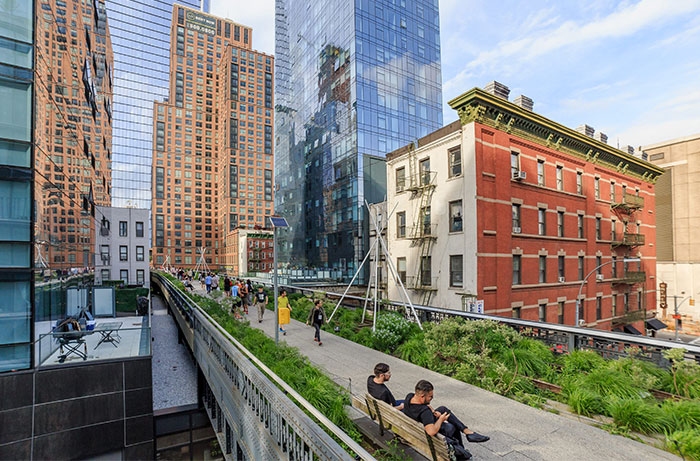 People walking on the high line with heritage buildings in the back